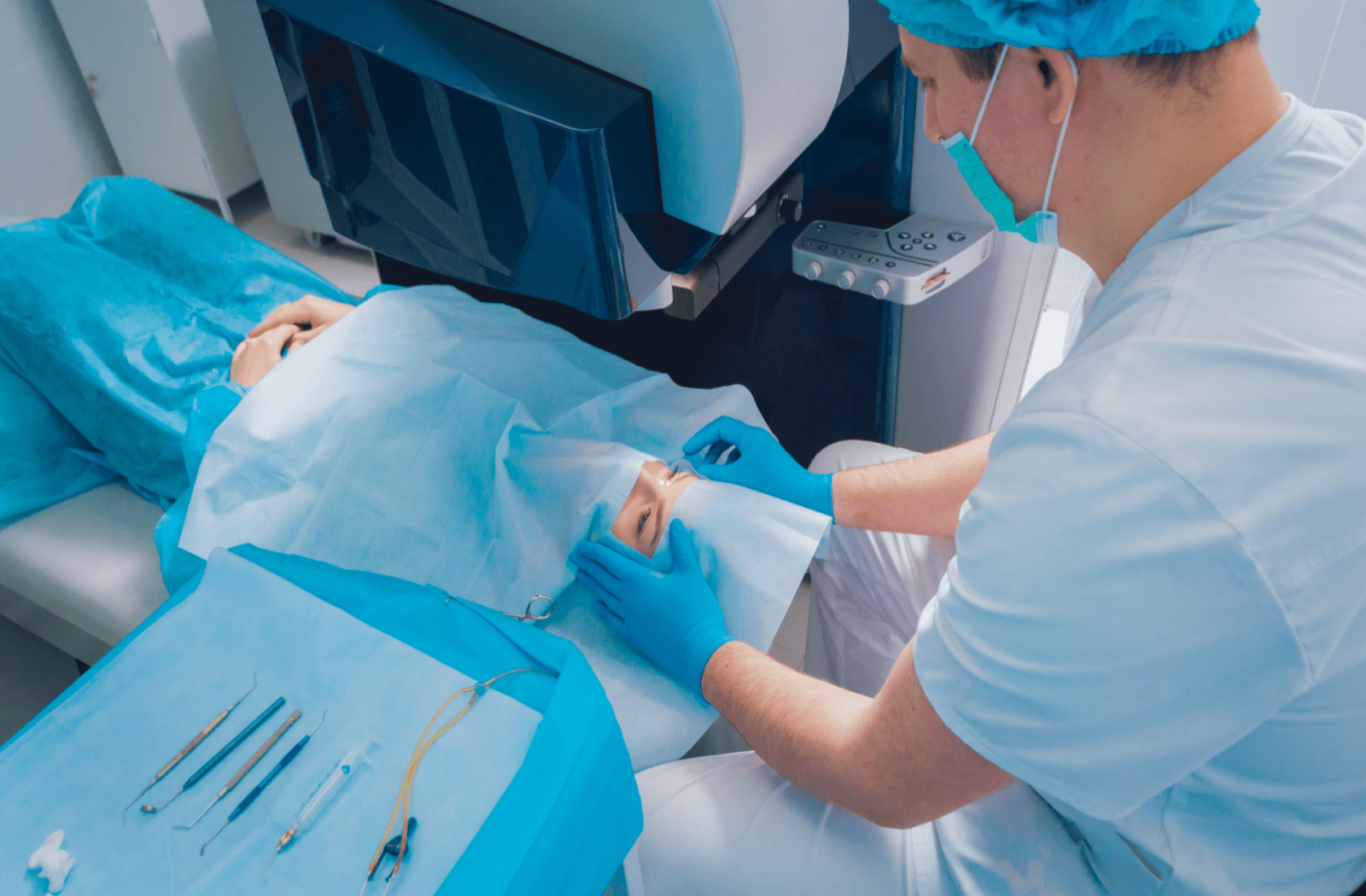 A medical professional in scrubs and gloves prepares a patient’s eye for cataract eye surgery in a clinic, with surgical instruments laid out on a blue sterile sheet nearby.