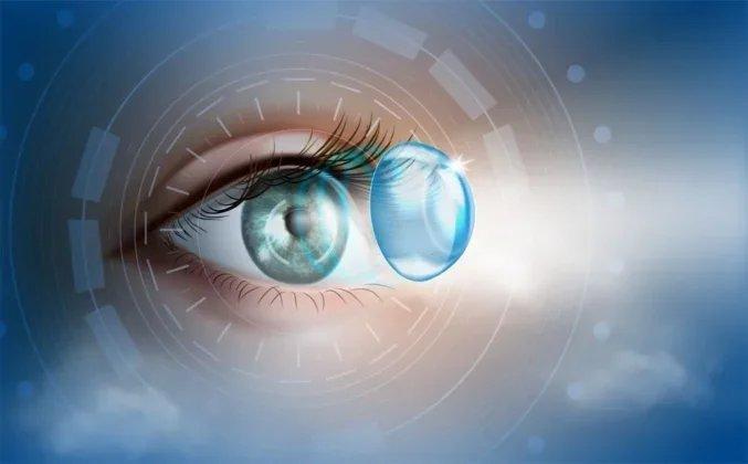 A digital illustration of a human eye with a lens implant hovering in front of it, emitting a bright beam of light, set against a blue futuristic background.