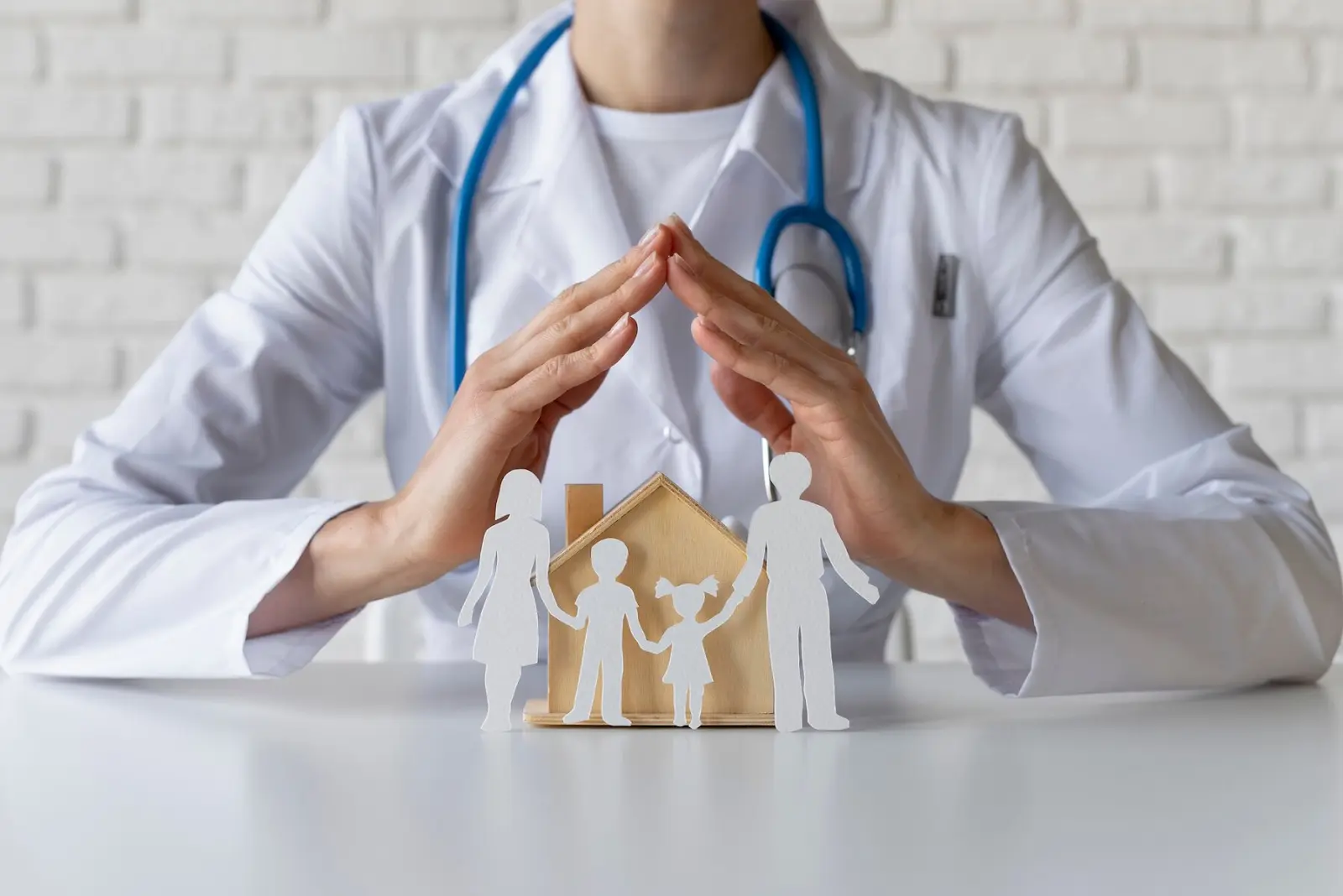 A doctor in a white coat with a stethoscope protects paper cutouts of a family and a house, symbolizing healthcare, family protection, and support for conditions like blurred vision needing cataract treatment.