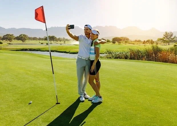 A man and woman in golf attire comparing LASIK and PRK laser eye surgery procedures on a smartphone.